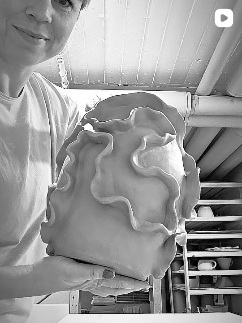 Lisa shaping a sculptural vase by hand in her studio.